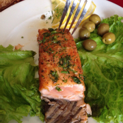 Cá hồi nướng sơ, bên ngoài khô bên trong mềm, rải thì là và ăn kèm olive. Phần rất lớn, dành cho 2 người ăn.